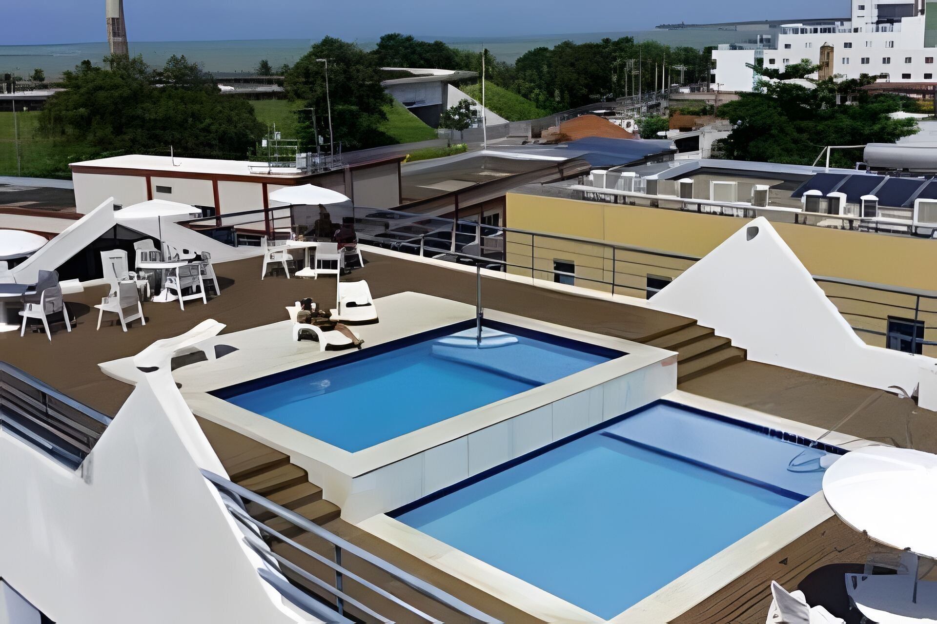 Uma piscina no terraço com espreguiçadeiras e vista para o mar.