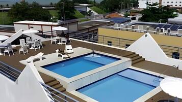 Uma piscina no terraço com espreguiçadeiras e vista para o mar.