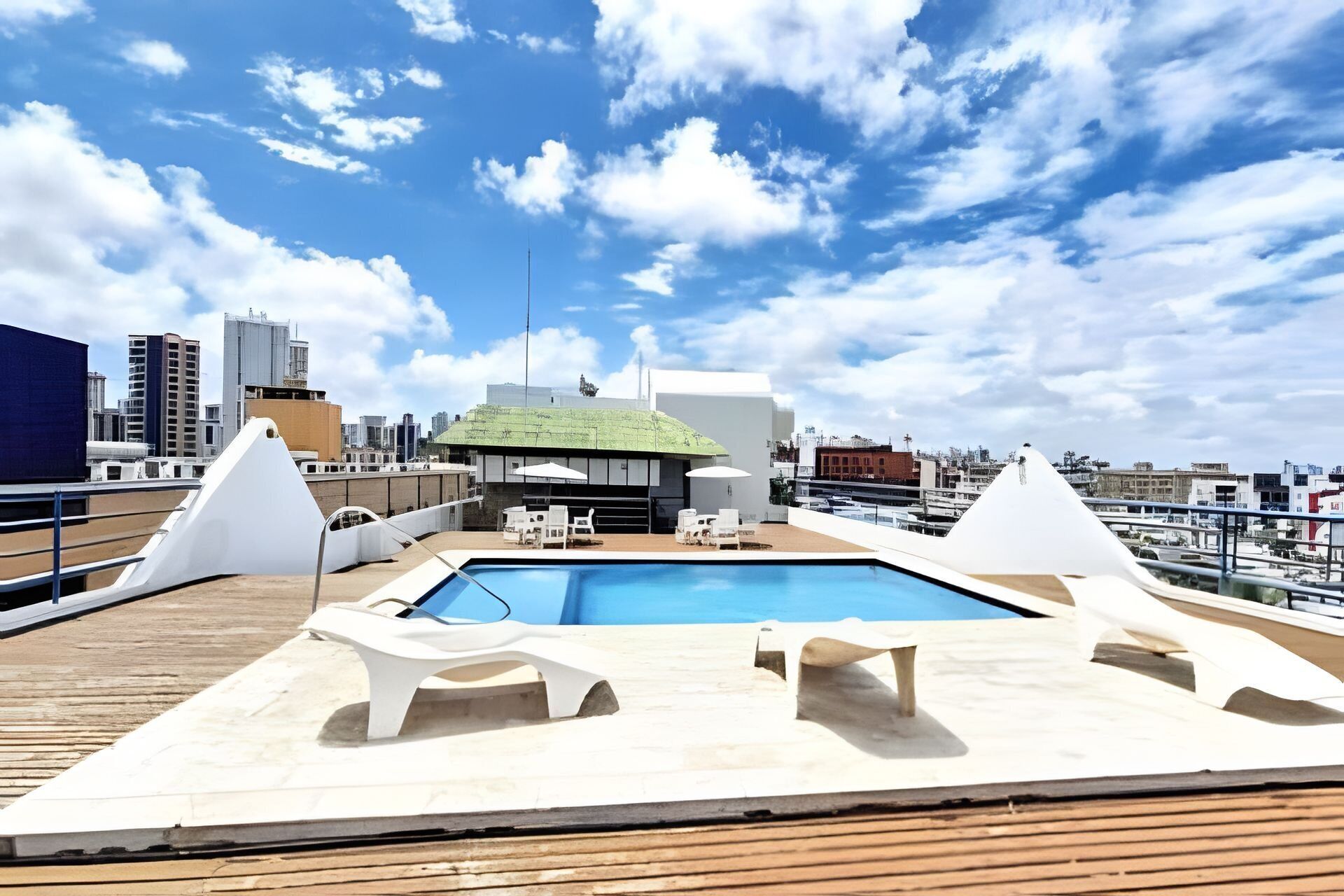 A rooftop pool area with lounge chairs and a view of the cityscape.