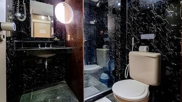 Un baño con lavamanos de mármol negro, inodoro y espejo con luz.