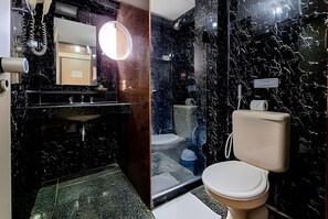 Ein Badezimmer mit einem schwarzen Marmorwaschbecken, einer Toilette und einem Spiegel mit Beleuchtung.