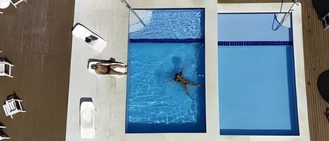 An aerial view of a swimming pool with two separate sections, a lifeguard chair, and lounge chairs.