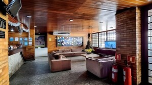 En modern inredning med ett träpanelat tak, en sittgrupp med soffor, en tv och en brandsläckare.