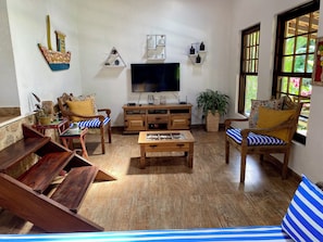 Ein Wohnzimmer mit Fernseher, Holzmöbeln, einem Blumentopf und einem Fenster mit Blick.