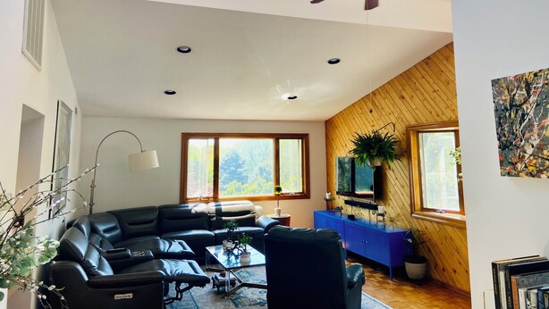 A spacious living area with a black leather sofa, a coffee table, a ceiling fan, and a blue cabinet. - Spacious 4-bedroom house in northern Westchester with sweeping views (Montrose)