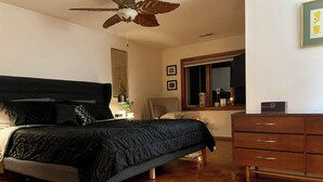 A bedroom with a bed, wooden floor, ceiling fan, dresser, window, and artwork on the wall. - Spacious 4-bedroom house in northern Westchester with sweeping views (Montrose)
