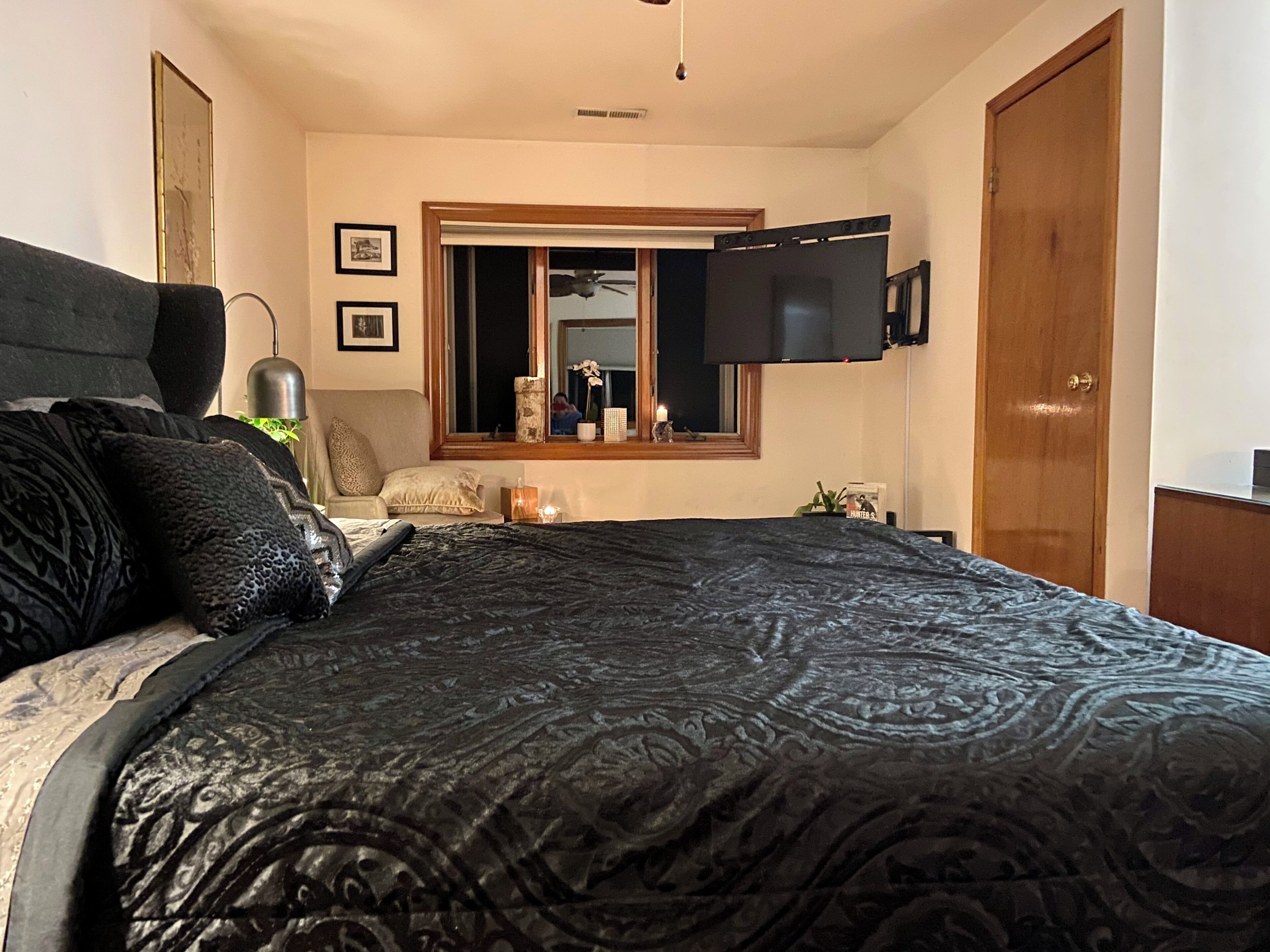 A bedroom with a bed, a window, a television, and a door.