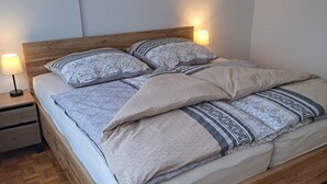 A neatly made bed with patterned bedding, a wooden headboard, and two bedside lamps. - Rieslingglück Vacation Rental (Trittenheim)