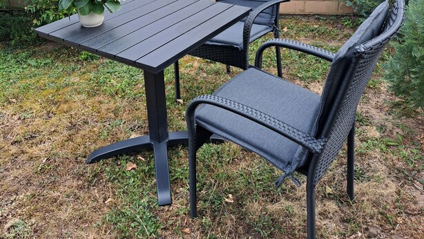 An outdoor patio with a table and chairs, a brick wall, and greenery. - Rieslingglück Vacation Rental (Trittenheim)