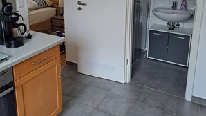 A modern kitchen with a coffee machine, wooden cabinets, and a grey tiled floor. - Rieslingglück Vacation Rental (Trittenheim)