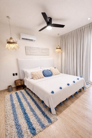 Ein Schlafzimmer mit Bett, Deckenventilator, Klimaanlage und einem großen Fenster mit Vorhängen.