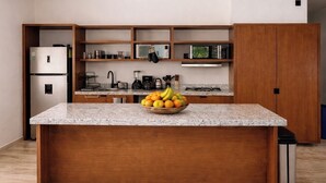 A kitchen with a granite countertop, a fruit bowl, a refrigerator, a microwave, and wooden cabinets. - Perfect 1-bedroom apartment with AC in welcoming Puerto Aventuras (Puerto Aventuras)