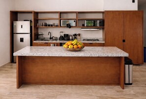 Eine Küche mit einer Granit-Arbeitsplatte, einer Obstschale, einem Kühlschrank, einer Mikrowelle und Holzschränken.