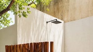 A wooden fence in a courtyard with a white wall and a hanging showerhead. - Perfect 1-bedroom apartment with AC in welcoming Puerto Aventuras (Puerto Aventuras)