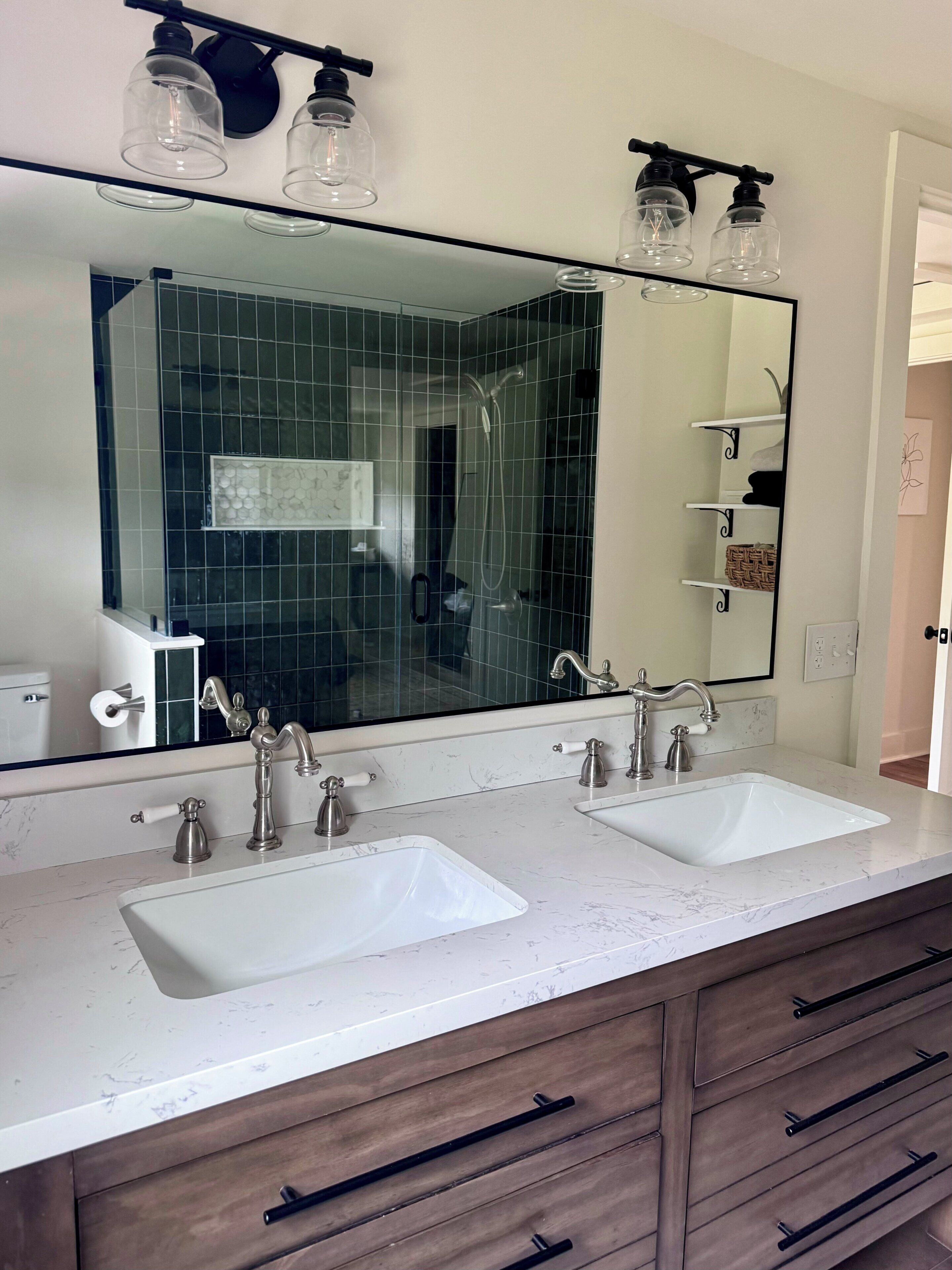 Une salle de bain avec deux lavabos, un grand miroir et une douche.