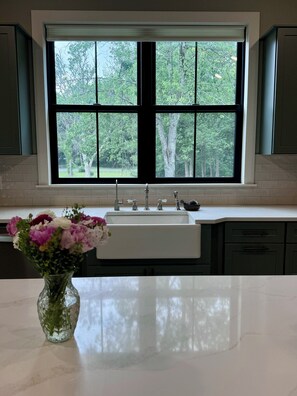A kitchen with a large window, a sink, and a vase with flowers on the counter.