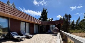 A modern building with a wooden deck, lounge chairs, and a hanging chair. - Casa de 4 dormitorios en Algarrobo, ideal para grupos familiares (Algarrobo)
