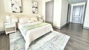 A bedroom with a bed, nightstands, a door, and a hallway. - Luxury Studio Apartment - 10 mins from Downtown (Houston)