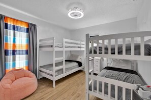 A room with bunk beds, a small seating area, and a ceiling light fixture. - Florida Vacation Home by Parks! (Kissimmee)