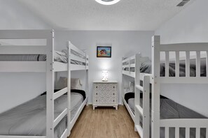 A room with bunk beds, a dresser, and a framed picture on the wall.