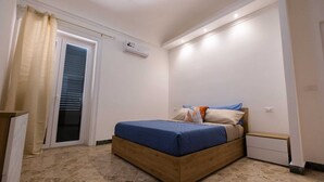 A bedroom with a bed, a nightstand, a window with blinds, and an air conditioning unit. - Experience Palermo in total comfort: a bright, cozy, and centrally located home. (Palermo)