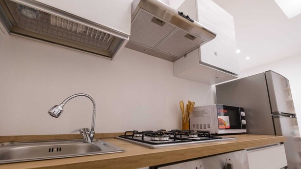 A modern kitchen with a stainless steel sink, gas stove, and a built-in microwave. - Experience Palermo in total comfort: a bright, cozy, and centrally located home. (Palermo)