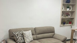 A beige sofa with a footrest, a patterned pillow, and a small table with a brown tablecloth. - Experience Palermo in total comfort: a bright, cozy, and centrally located home. (Palermo)