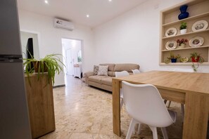 A living room with a sofa, a dining table with chairs, a wooden cabinet, and a shelf with decorative items. - Experience Palermo in complete comfort: a bright, cozy, and centrally located home. (Palermo)