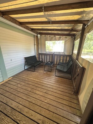 A covered porch with wooden flooring, a bench, and a table. - 2-Bedroom Family Mobile Home – Peaceful & Natural Setting in Castillonnès (Castillonnès)