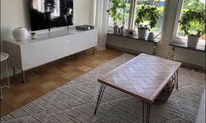Une cuisine moderne dotée d’un téléviseur à écran plat, de meubles blancs et d’une table au motif en chevrons.