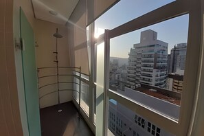 Un balcon avec vue sur la ville, une rambarde et une lampe sur pied.