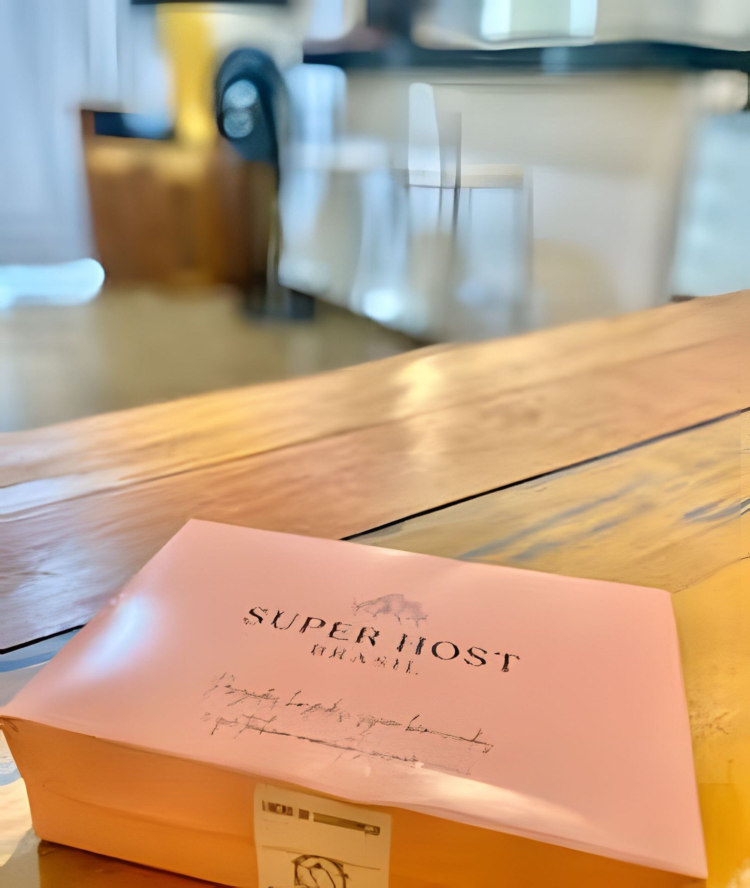 Een roze envelop met de tekst 'SUPER HOST' op een houten tafel.