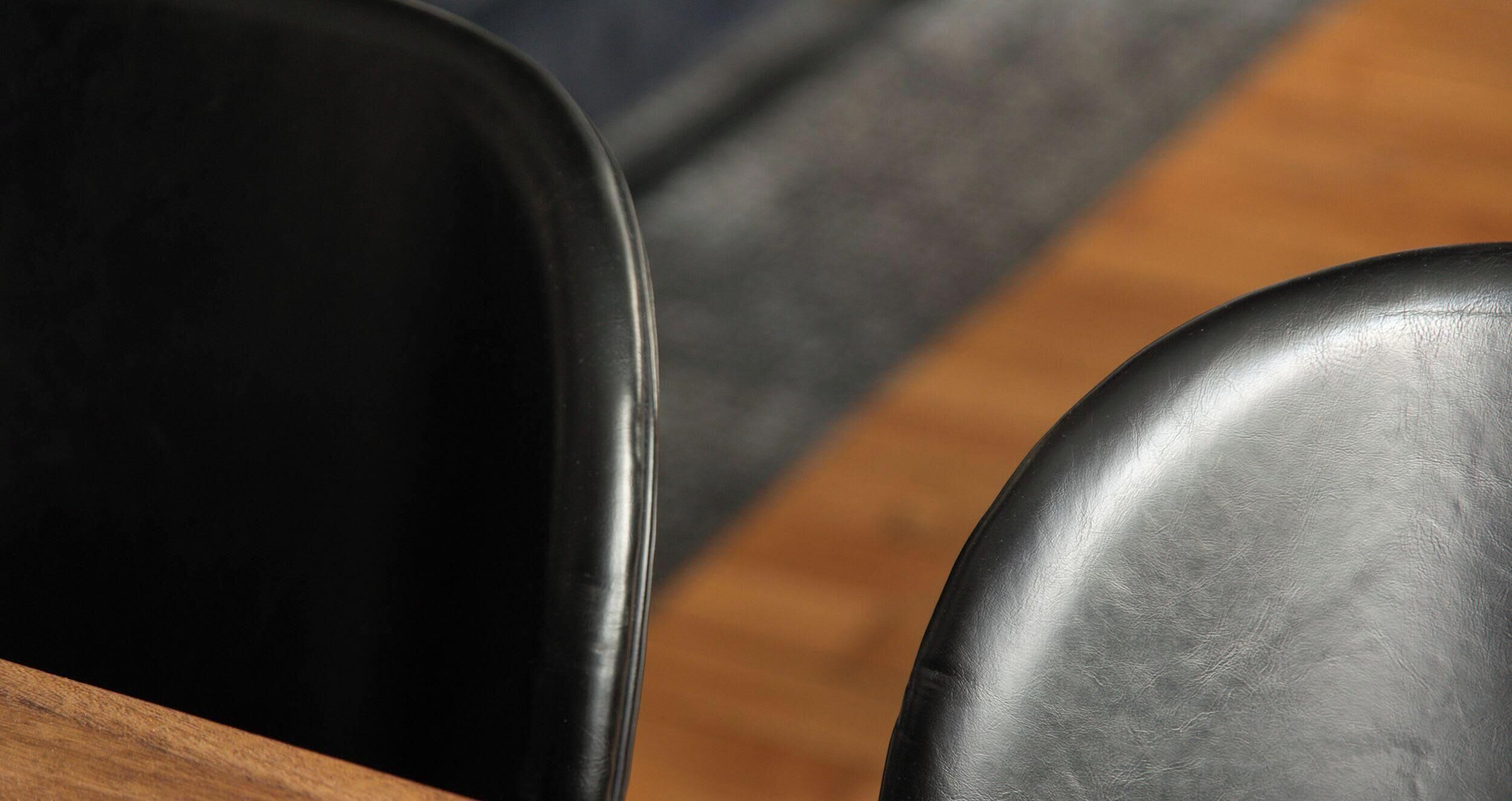 A close-up of a black chair with a wooden table leg.