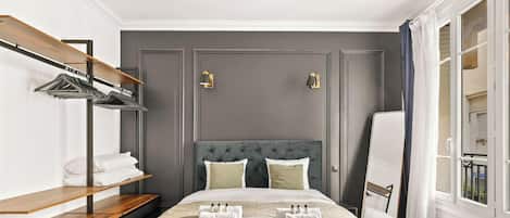 Une chambre d’hôtel avec un lit, une armoire, une étagère avec des serviettes et une fenêtre.