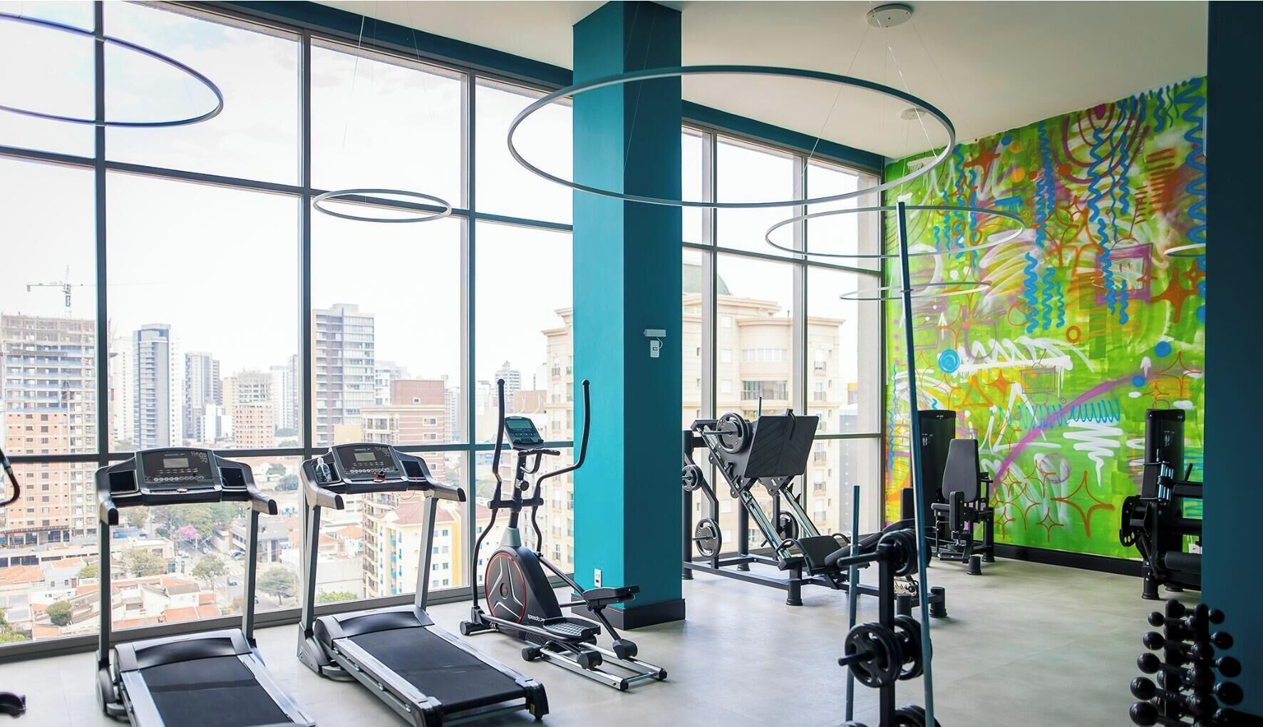 Uma academia com esteiras, elípticos e equipamentos de musculação.