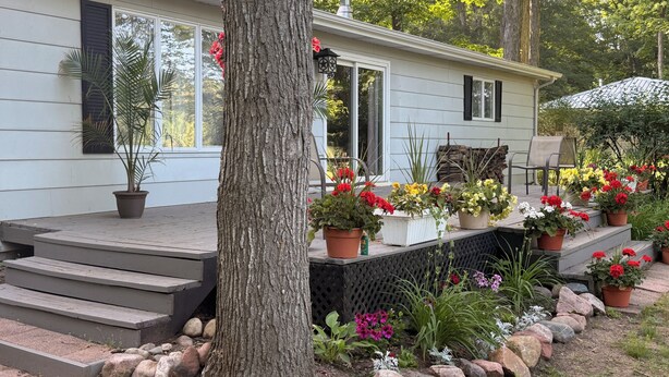 A house with a porch, potted plants, and a garden. - Riverfront escape at Q’s River Place, a 3 bedroom year round getaway (Hersey)