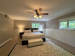 A bedroom with a bed, a ceiling fan, two windows, a nightstand, and a bedside table. - Riverfront escape at Q’s River Place, a 3 bedroom year round getaway (Hersey)