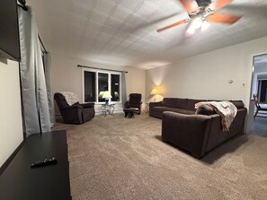 Ein Wohnzimmer mit Deckenventilator, zwei Sofas, einem Tisch und einer Lampe.