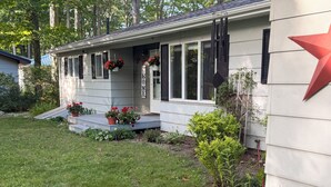 A house with a front porch, steps, potted plants, and a red star decoration. - Riverfront escape at Q’s River Place, a 3 bedroom year round getaway (Hersey)
