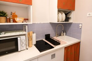 Une cuisine équipée d’un four à micro-ondes, d’une cuisinière, d’un évier et de divers ustensiles.