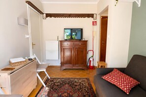 A living room with a sofa, a television, a wooden cabinet, a small table, and a patterned rug. - Via Medal: 1BR apt in the heart of Bardonecchia (Bardonecchia)