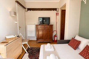 A bedroom with a bed, a wooden dresser, a television, a fire extinguisher, and a small desk with a lamp. - Via Medal: 1BR apt in the heart of Bardonecchia (Bardonecchia)