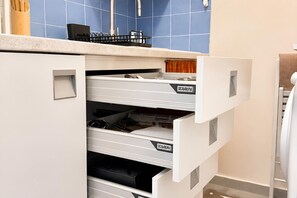 A kitchen with white cabinetry, a blue tiled backsplash, and a countertop with a utensil holder. - Via Medal: 1BR apt in the heart of Bardonecchia (Bardonecchia)