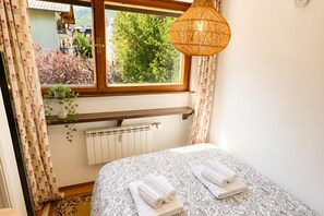 A bedroom with a bed, a window with curtains, a radiator, and a hanging light fixture. - Via Medal: 1BR apt in the heart of Bardonecchia (Bardonecchia)