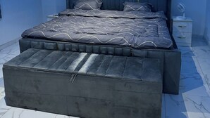 A modern bedroom with a large bed, a ceiling fan, and a nightstand. - Mavis’s Lodge Air BnB (Kumasi)