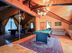 Ein Billardtisch in einem Raum mit Holzdielen und einer geneigten Decke.