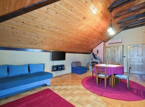Una sala de estar acogedora con techo de madera, un sofá azul, una chimenea y una mesa de comedor con sillas.