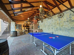 Ein Tischtennis-Tisch in einem Raum mit Steinwand und Holzbalken.