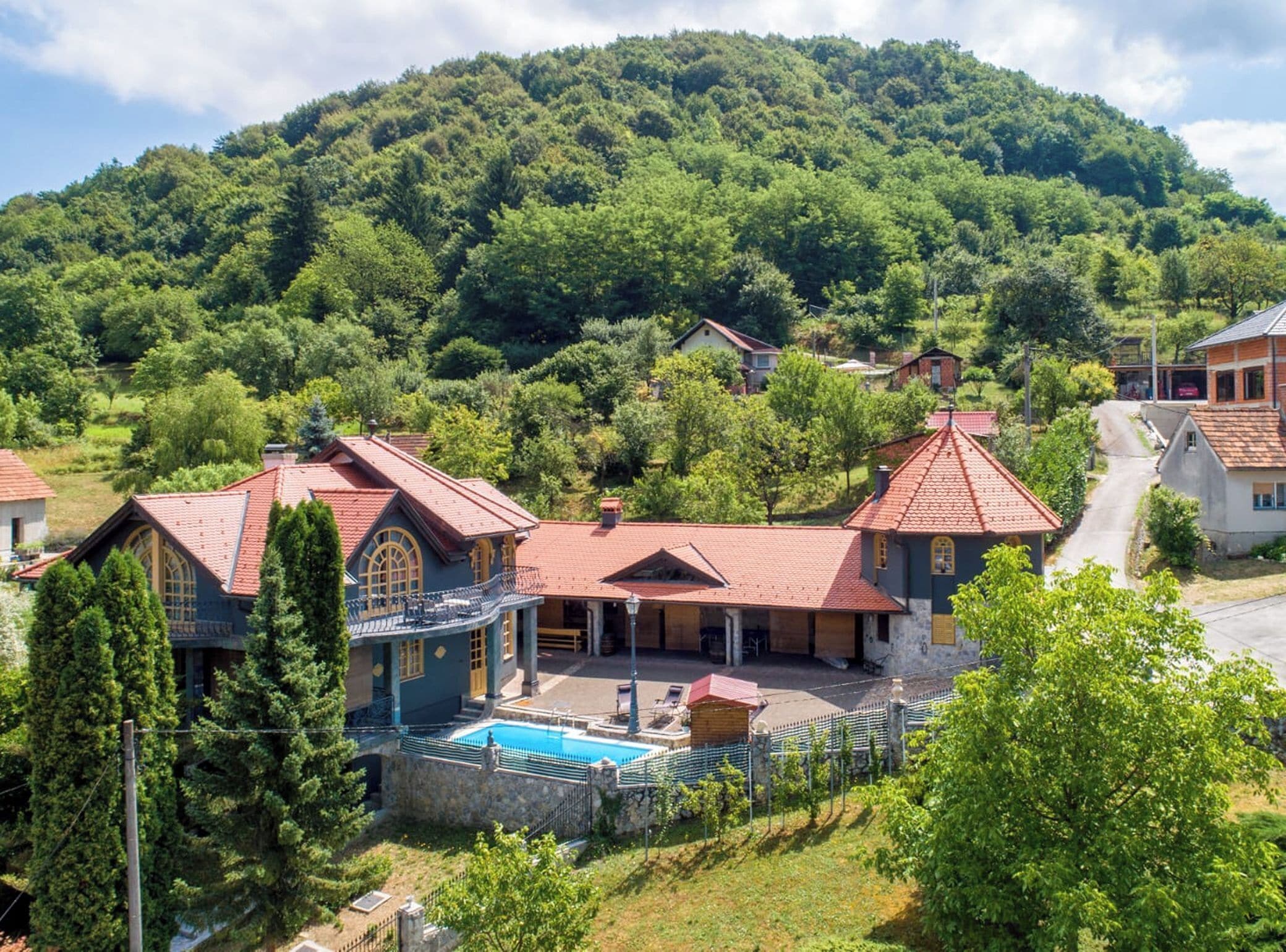 A residential area with houses, a swimming pool, and a mountain backdrop.