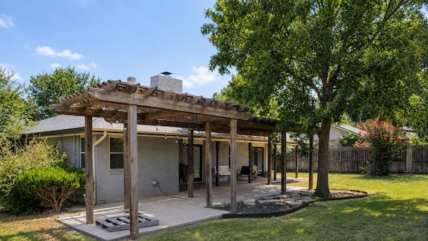 A covered patio with a wooden pergola, a barbecue area, and a grassy yard.